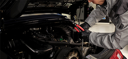 mechanic checking car engine under hood with a pair of pliers