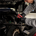 mechanic checking car engine under hood with a pair of pliers