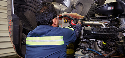 back view of mechanic inspecting the truck engine