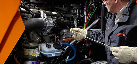 mechanic inspecting front of truck with a dipstick