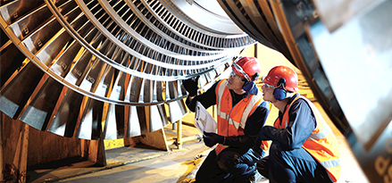 two engineers inspecting turbine from below
