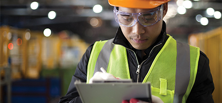 engineer in safety gear taking notes on a clipboard