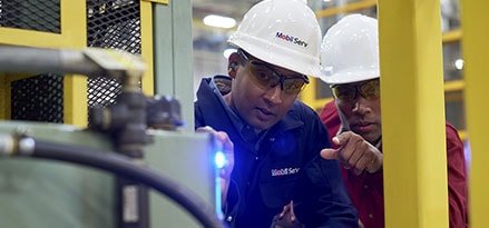 mobil serv engineer and customer inspecting equipment with flashlight