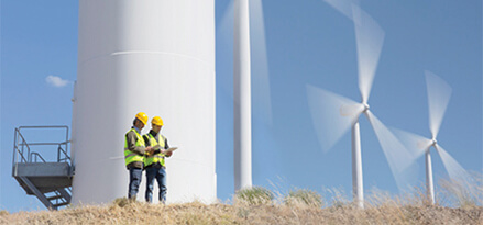 2 men talking beside a wind turbine