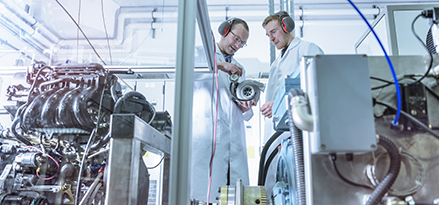 two scientists studying turbocharger engine in a lab